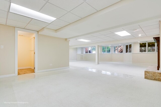 basement with a drop ceiling, carpet flooring, and baseboards