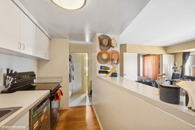 kitchen featuring black electric range oven, dishwashing machine, light countertops, light wood-style flooring, and white cabinets