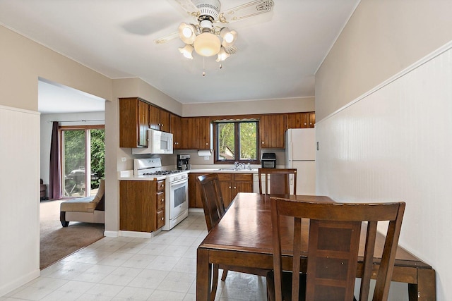 kitchen featuring white appliances, a ceiling fan, light countertops, and healthy amount of natural light