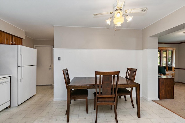 dining room with a ceiling fan, ornamental molding, wainscoting, and light flooring