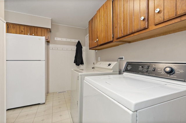 clothes washing area with separate washer and dryer, cabinet space, and light flooring