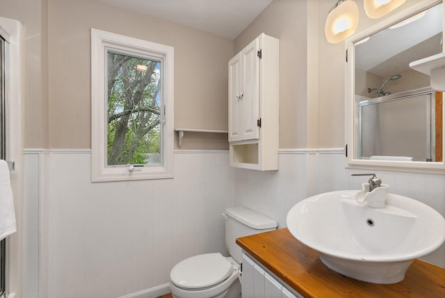 bathroom featuring a shower stall, wainscoting, toilet, and vanity