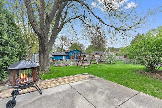 view of yard featuring an outdoor fire pit, a playground, a patio, a shed, and an outbuilding