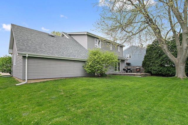 back of property with a shingled roof, a lawn, and a patio