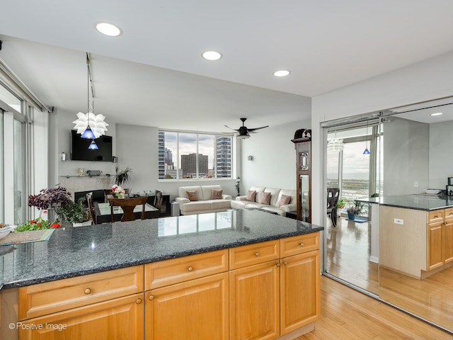 1515 S Prairie Ave Unit 1306, Chicago, IL 60605 - kitchen featuring light wood finished floors, a ceiling fan, dark stone counters, a fireplace, and open floor plan