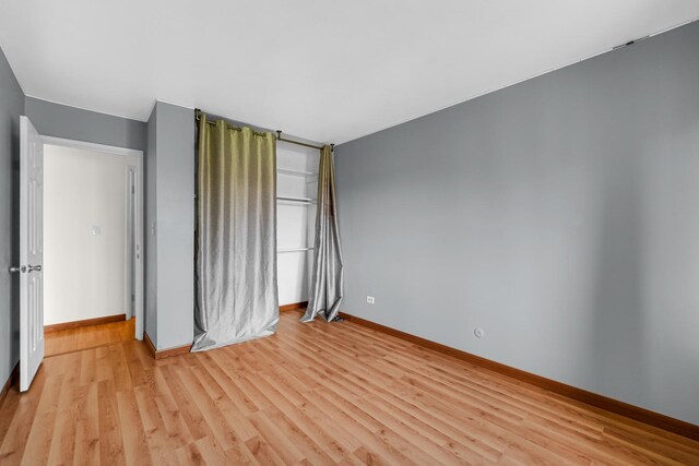 unfurnished bedroom with light wood-type flooring and baseboards