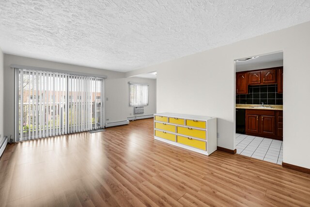 unfurnished room featuring light wood-type flooring, a textured ceiling, a sink, baseboards, and a baseboard heating unit