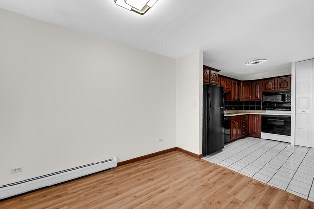 kitchen with black appliances, a baseboard radiator, light countertops, light wood-style flooring, and tasteful backsplash