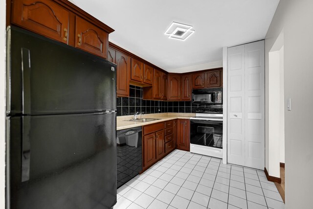 kitchen featuring black appliances, light countertops, a sink, light tile patterned floors, and backsplash