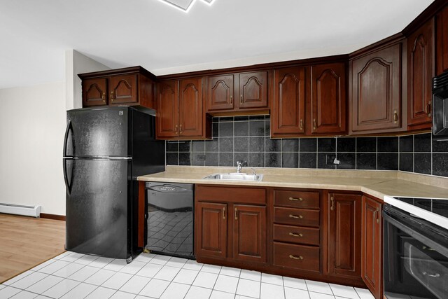 kitchen with black appliances, a sink, baseboard heating, and light countertops