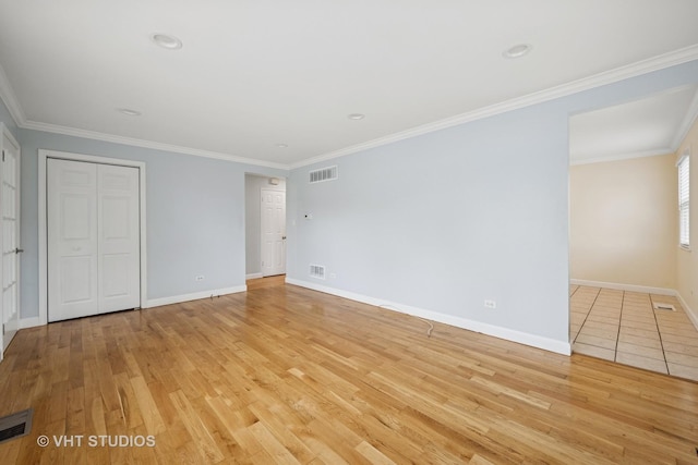 unfurnished bedroom with crown molding, light wood-style floors, visible vents, and baseboards