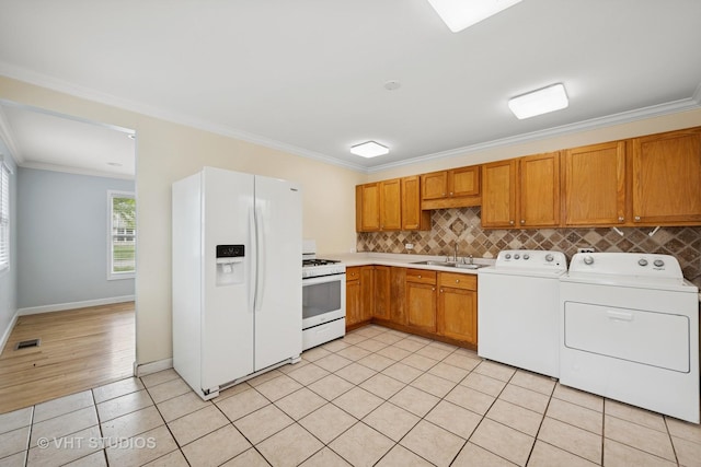 kitchen featuring separate washer and dryer, ornamental molding, a sink, and white appliances