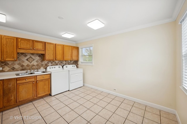 laundry room with baseboards, ornamental molding, washer and dryer, and a sink