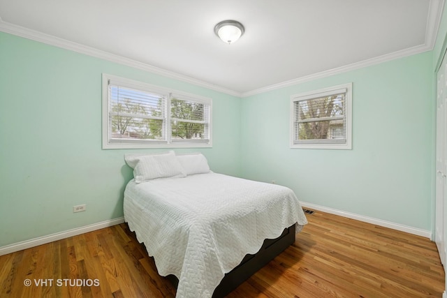 bedroom featuring baseboards, crown molding, and wood finished floors