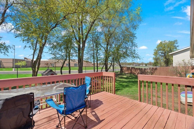 wooden terrace featuring a fenced backyard, outdoor dining space, and a lawn