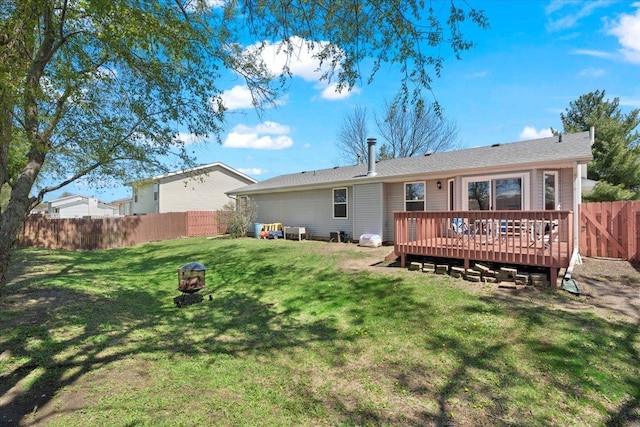 rear view of house featuring a yard, a wooden deck, and a fenced backyard