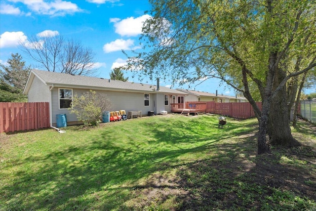 rear view of house with a yard, a wooden deck, and a fenced backyard