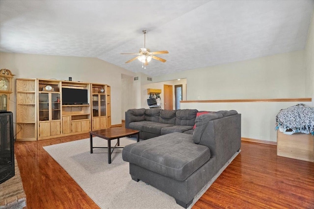living room with a ceiling fan, lofted ceiling, baseboards, visible vents, and wood finished floors