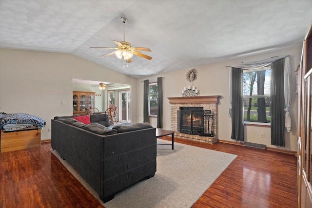 living area featuring a fireplace, ceiling fan, plenty of natural light, and wood finished floors
