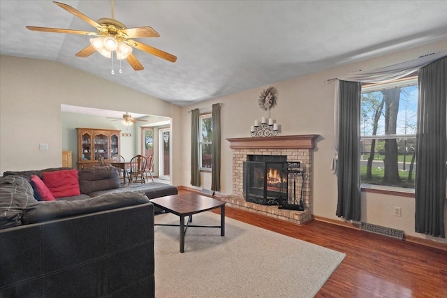 living room featuring vaulted ceiling, plenty of natural light, visible vents, and wood finished floors