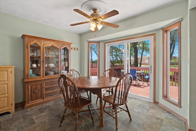 dining space with baseboards, ceiling fan, and stone finish floor