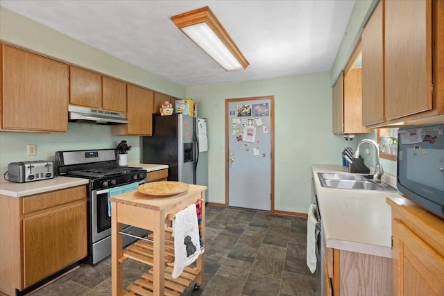 kitchen featuring under cabinet range hood, a sink, light countertops, and appliances with stainless steel finishes