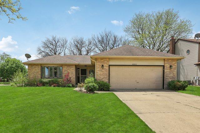 single story home featuring an attached garage, driveway, brick siding, and a front lawn