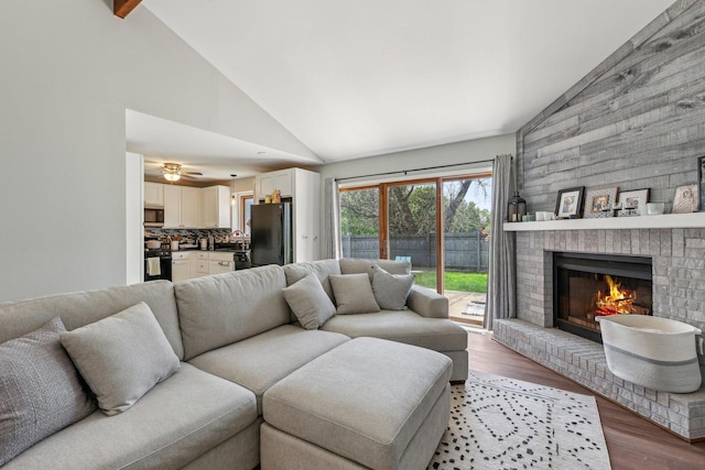 living area featuring light wood-style flooring, a fireplace, and high vaulted ceiling