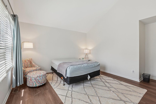 bedroom with wood finished floors, baseboards, and vaulted ceiling