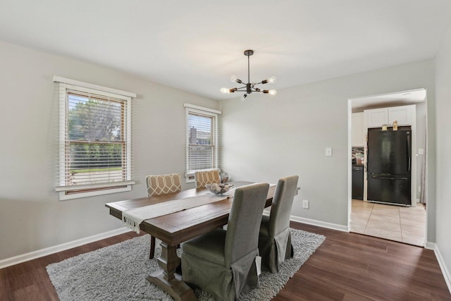 dining room featuring a chandelier, light wood finished floors, and baseboards