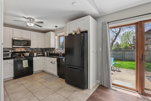 kitchen featuring black appliances, dark countertops, a sink, and healthy amount of natural light