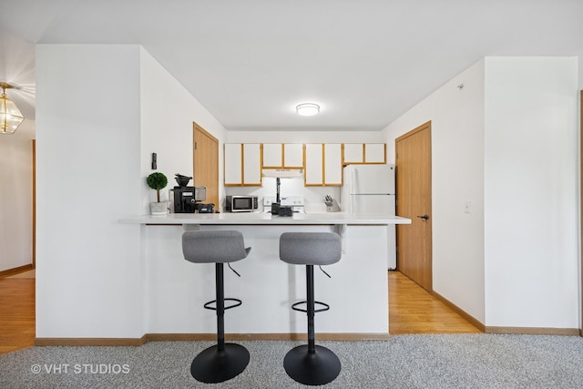 1443 Spring Brook Ct Unit 1B, Round Lake Beach, IL 60073 - kitchen with white appliances, a kitchen bar, a peninsula, and light countertops