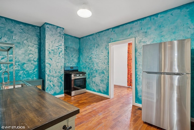 1751 W 21st Pl, Chicago, IL 60608 - kitchen with stainless steel appliances, wood finished floors, dark countertops, baseboards, and wallpapered walls
