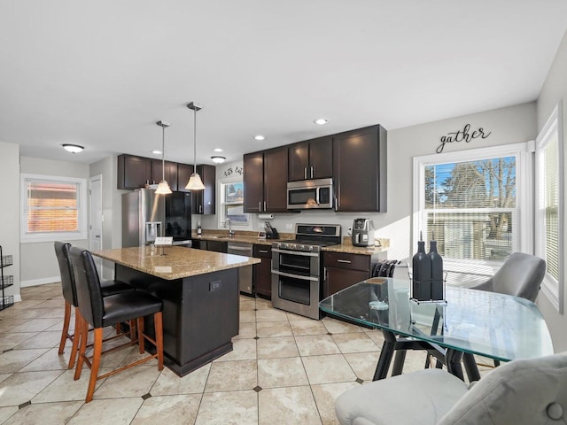 417 Oglesby Ave, Calumet City, IL 60409 - kitchen with light stone countertops, dark brown cabinetry, a kitchen breakfast bar, a kitchen island, and stainless steel appliances
