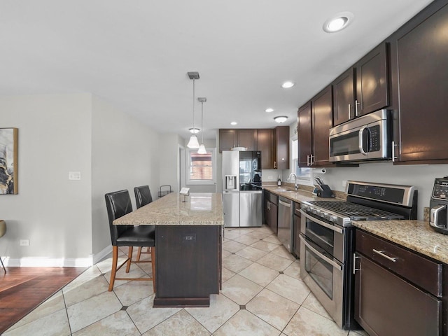 417 Oglesby Ave, Calumet City, IL 60409 - kitchen with a center island, dark brown cabinetry, a sink, a kitchen bar, and appliances with stainless steel finishes