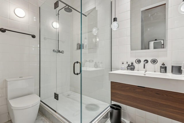 full bath with tile walls, a shower stall, toilet, and vanity