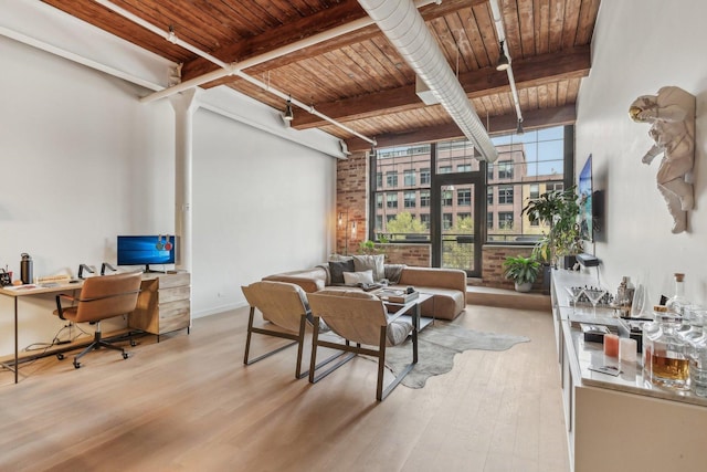 living room featuring beam ceiling, wood finished floors, an office area, wood ceiling, and baseboards
