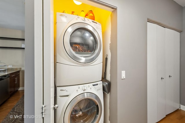 washroom featuring laundry area, stacked washing maching and dryer, and wood finished floors