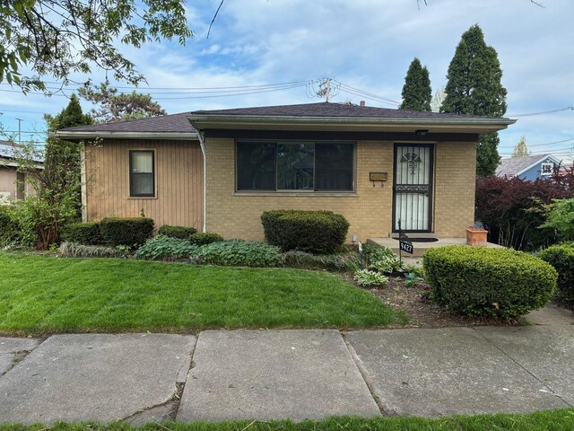 view of front facade with brick siding and a front yard