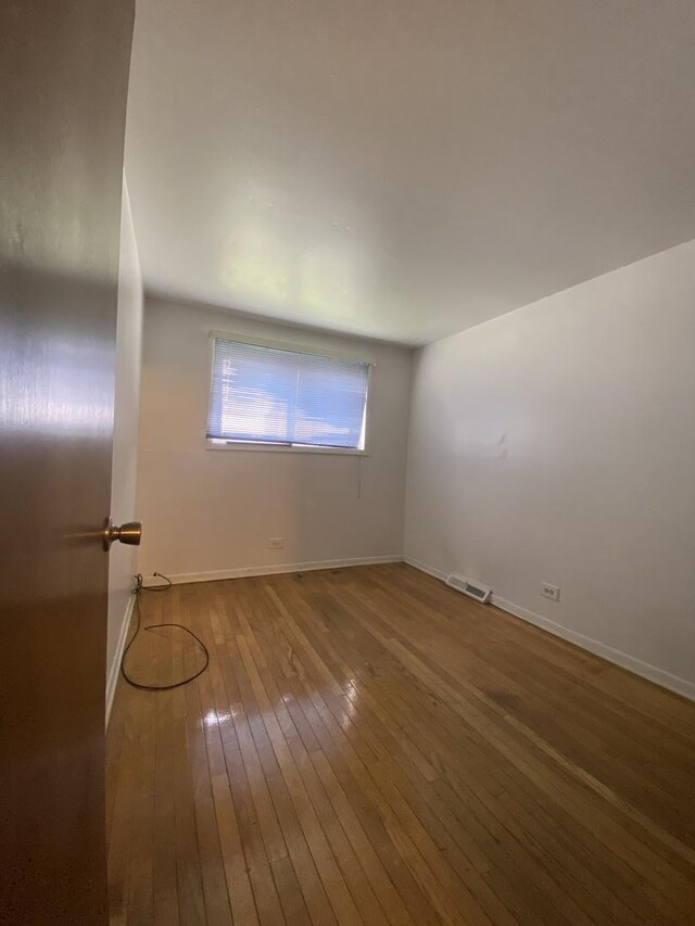 empty room with hardwood / wood-style floors and baseboards