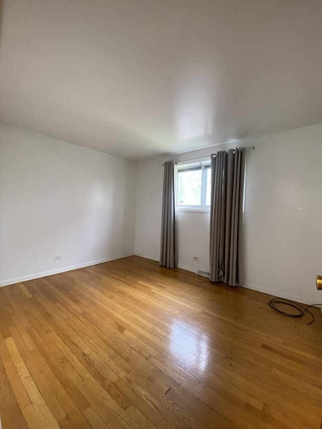 spare room featuring light wood finished floors and baseboards