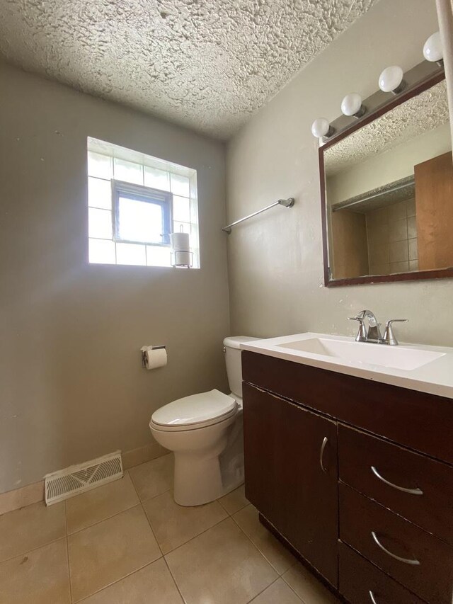 bathroom featuring tile patterned floors, toilet, a textured ceiling, and vanity