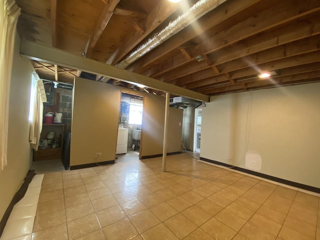 basement featuring washer / clothes dryer, light tile patterned floors, and baseboards