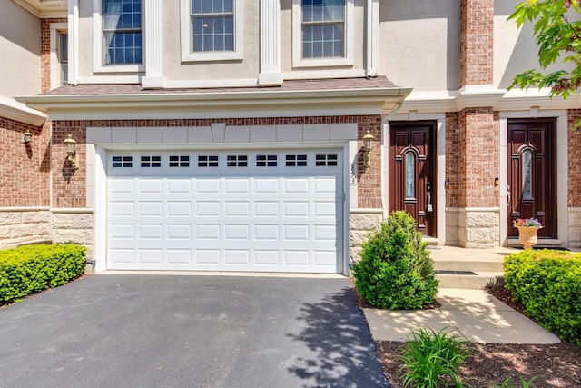 893 S Plum Grove Rd, Palatine, IL 60067 - view of front facade featuring asphalt driveway, an attached garage, stucco siding, and brick siding