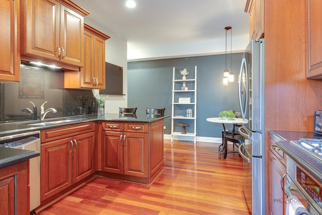 893 S Plum Grove Rd, Palatine, IL 60067 - kitchen featuring appliances with stainless steel finishes, light wood finished floors, brown cabinetry, backsplash, and a peninsula
