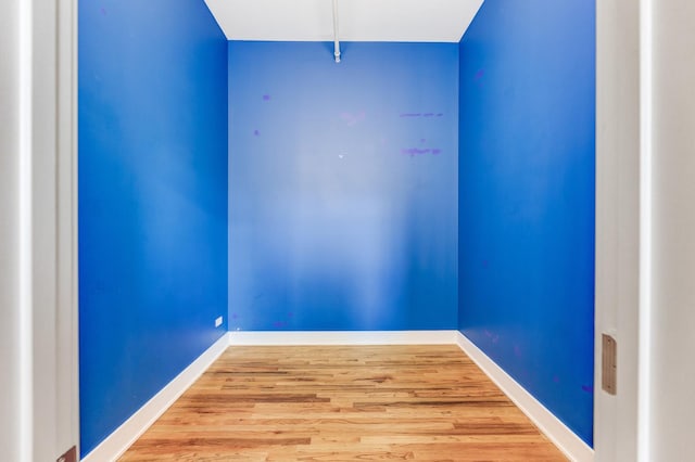 spare room with baseboards and wood finished floors