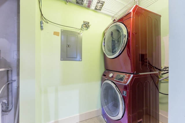 laundry area featuring baseboards, laundry area, stacked washer and clothes dryer, and electric panel