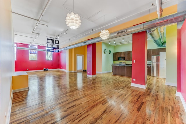 interior space with baseboards, light wood-style floors, visible vents, and track lighting