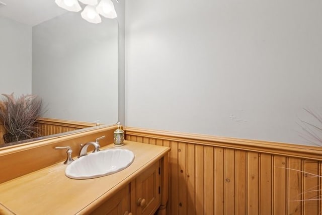 bathroom featuring a wainscoted wall, vanity, and wooden walls