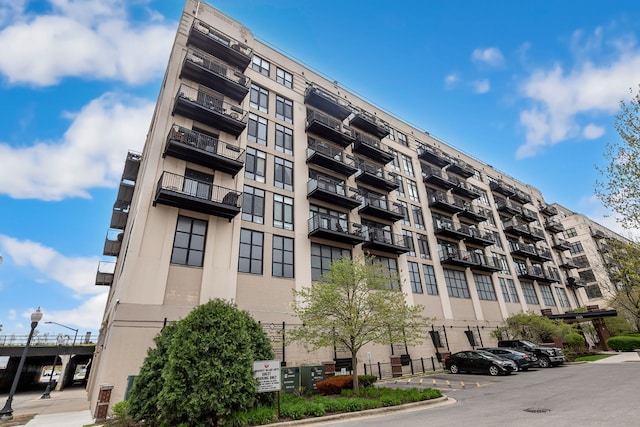 view of apartment building / complex featuring uncovered parking and central AC unit